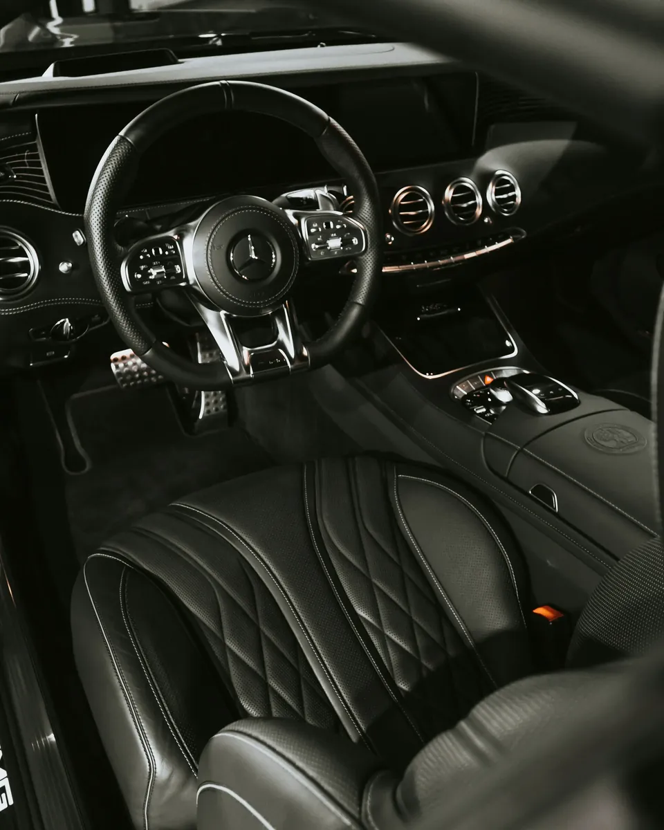 A dark leather interior with the steering wheel in frame
