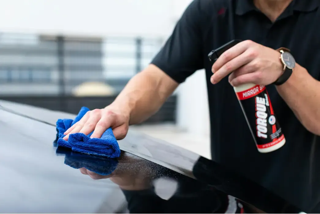 A hand working product across wet paint with a microfibre cloth