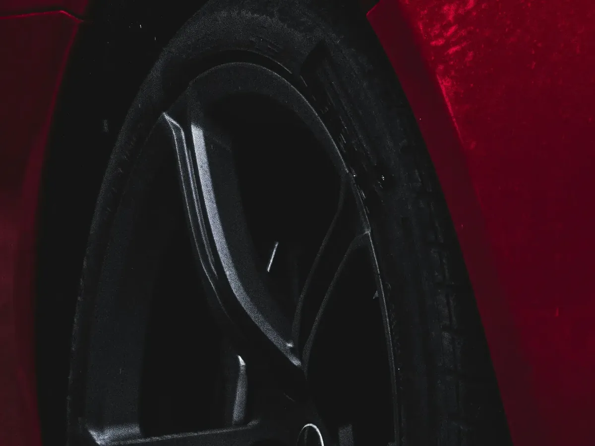 A dark alloy wheel and arch on a wet red car